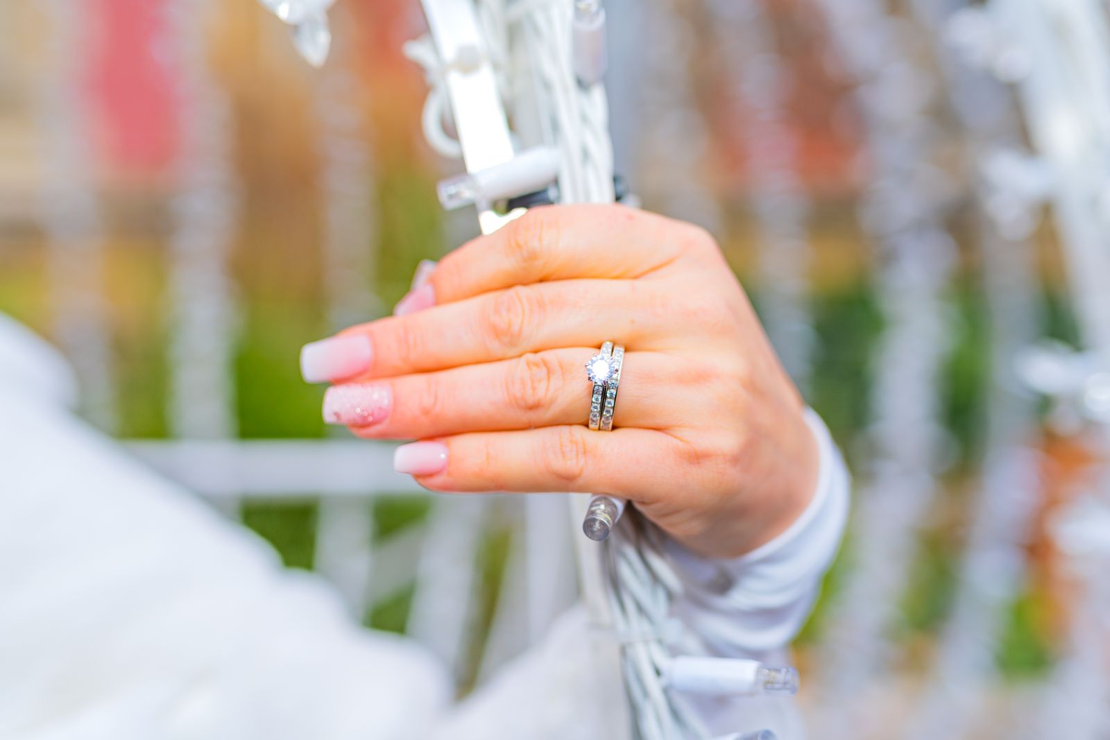 Elegant bride's hand showcasing diamond ring amidst wedding decorations.